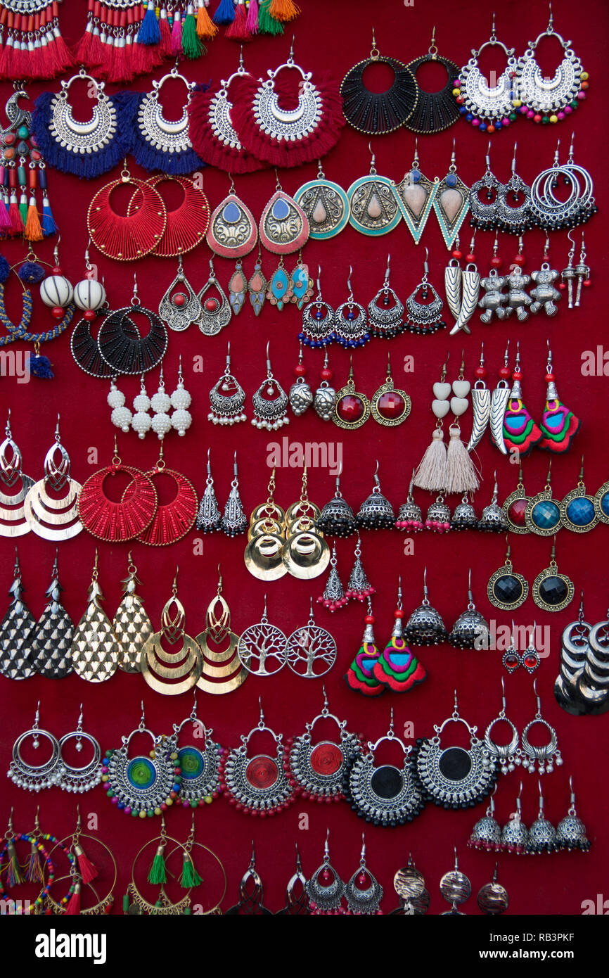 Closeup of different earings hanging on red fabric showcase Stock Photo