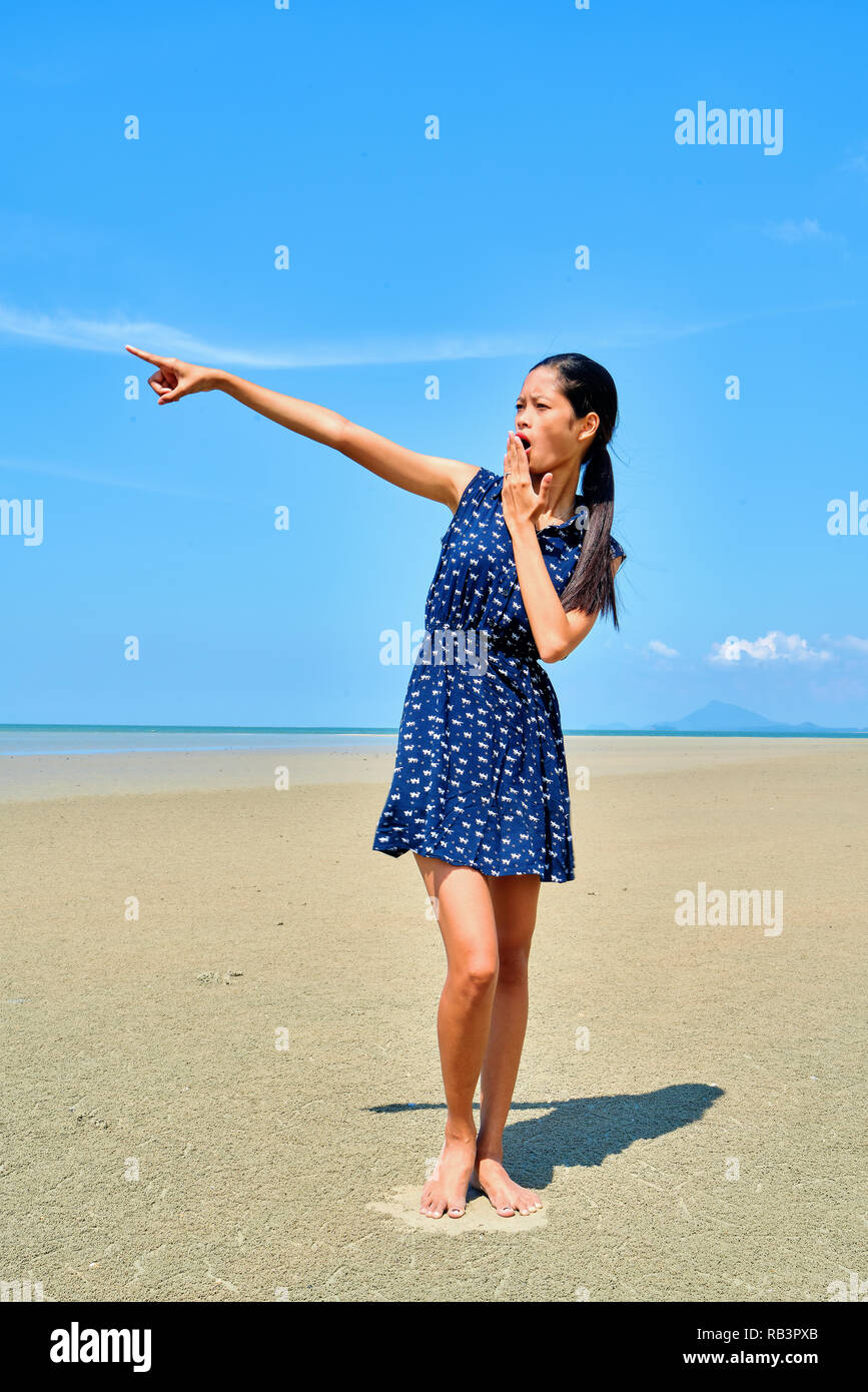 Beautiful woman posing - shocked, pointing somewhere and covering the mouth Stock Photo