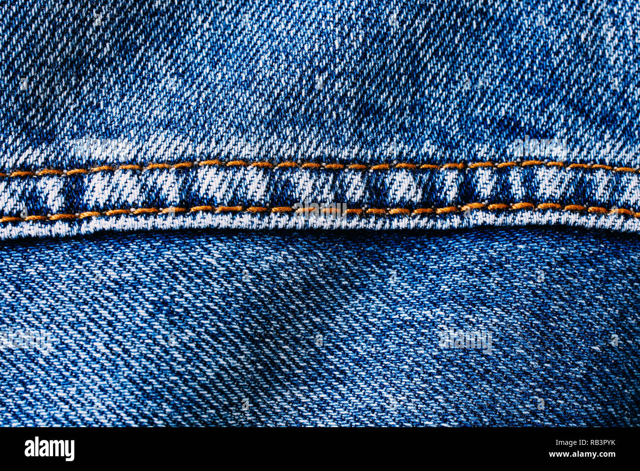 Blue denim jeans with middle brown yellow color sewing thread seam macro  closeup textile background Stock Photo - Alamy