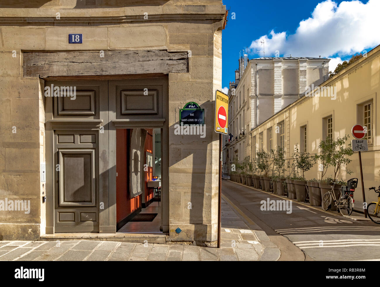 Open wooden doorway next to an narrow street on Rue Saint-Louis en l'Île on a summers morning in Paris Stock Photo