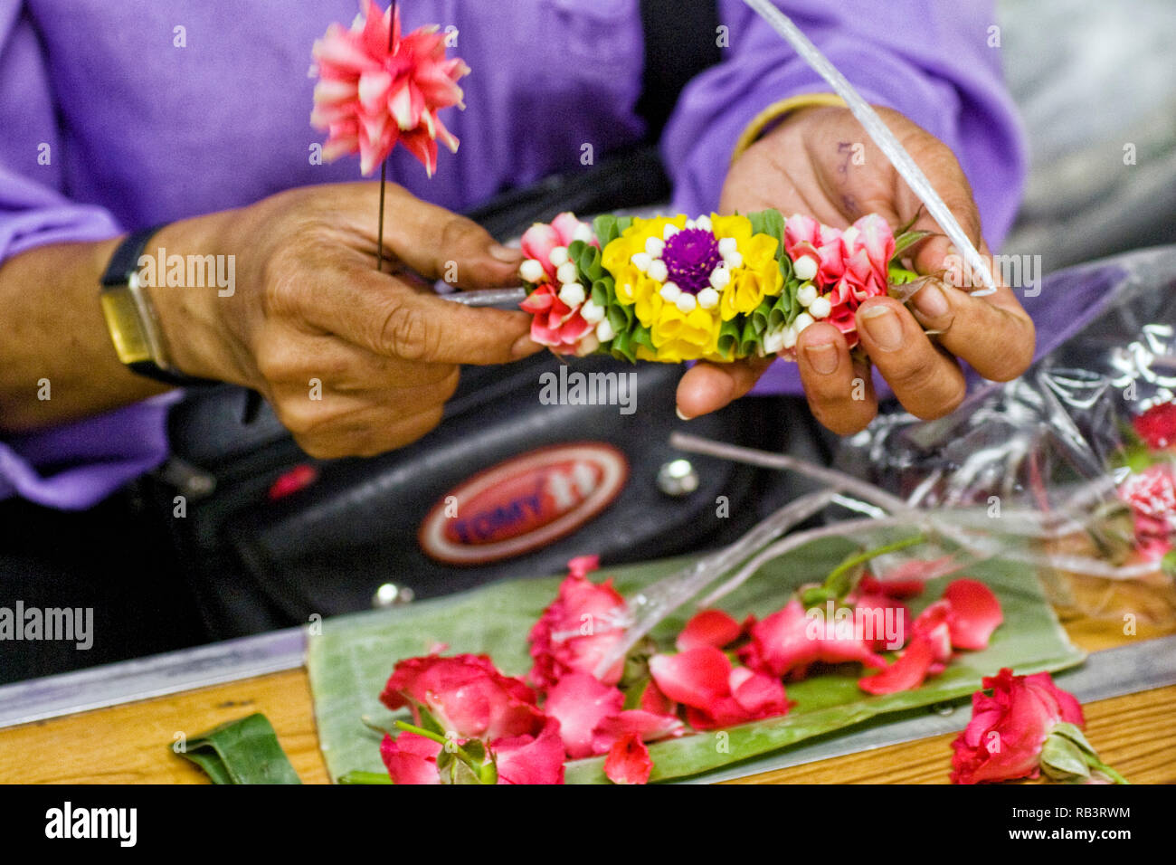 arranging flowers for a phuang malai floral garland at the Pak Khlong Talat flower market in Bangkok, Thailand Stock Photo