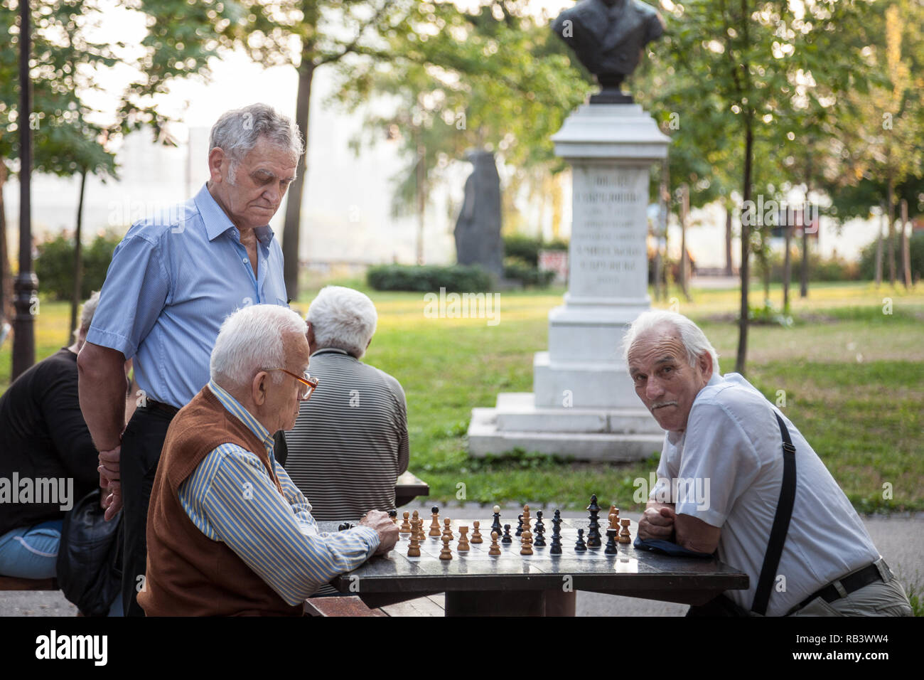 BELGRADE, SERBIA - JULY 11, 2018: Old senior men playing chess in a park of Kalemegdan fortress, in Belgrade, Serbia. Kalemegdan is one of the main la Stock Photo
