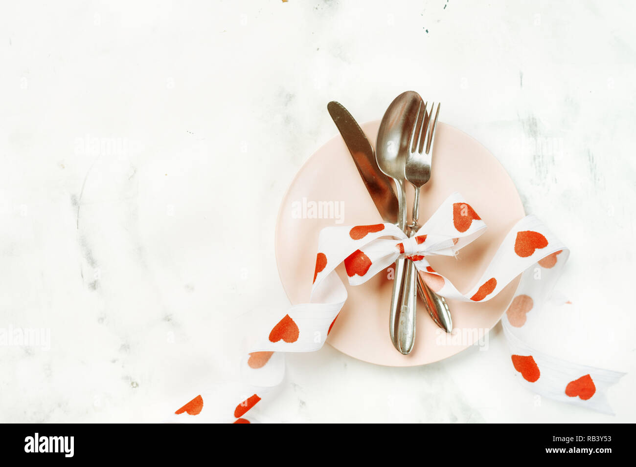 Festive table setting with cutlery and pink plate for Valentines Day Stock Photo