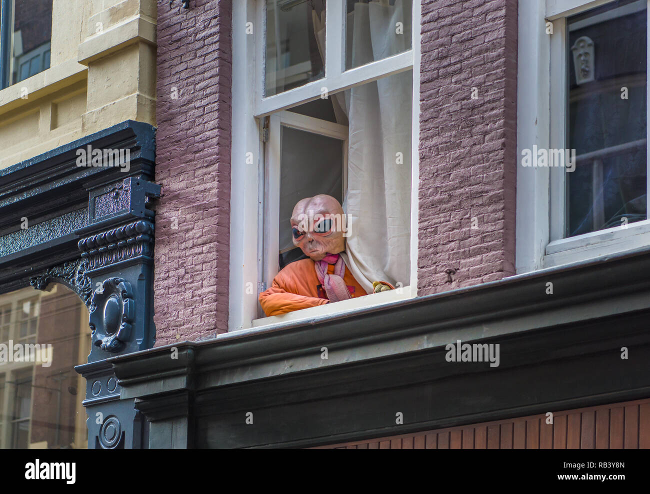 Alien ET at the window watching pedestrian in the street in Amsterdam Stock Photo