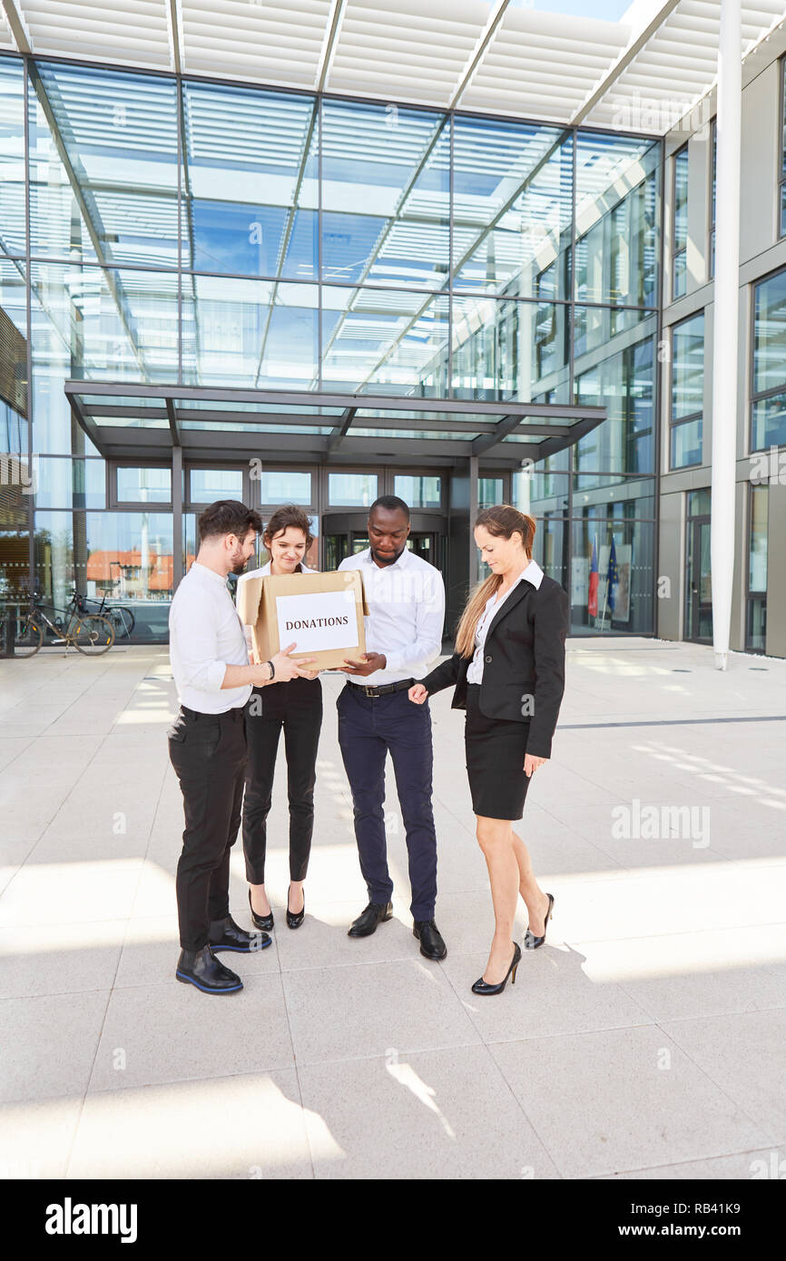 Business team with a box with a donation stands in front of the corporate building Stock Photo