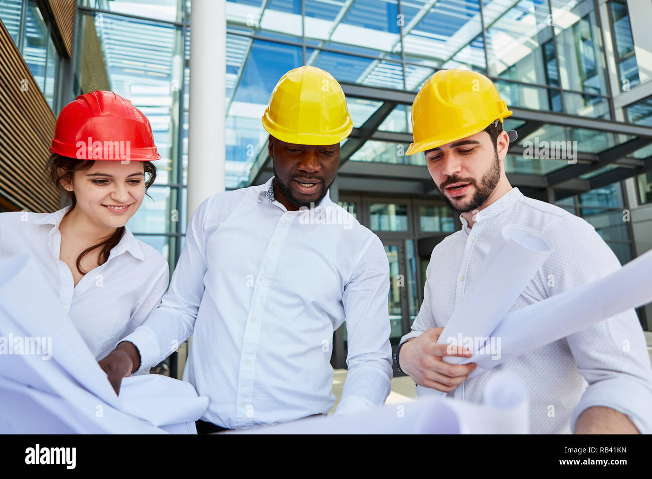 Architects Team in a construction planning meeting looking at construction drawings Stock Photo