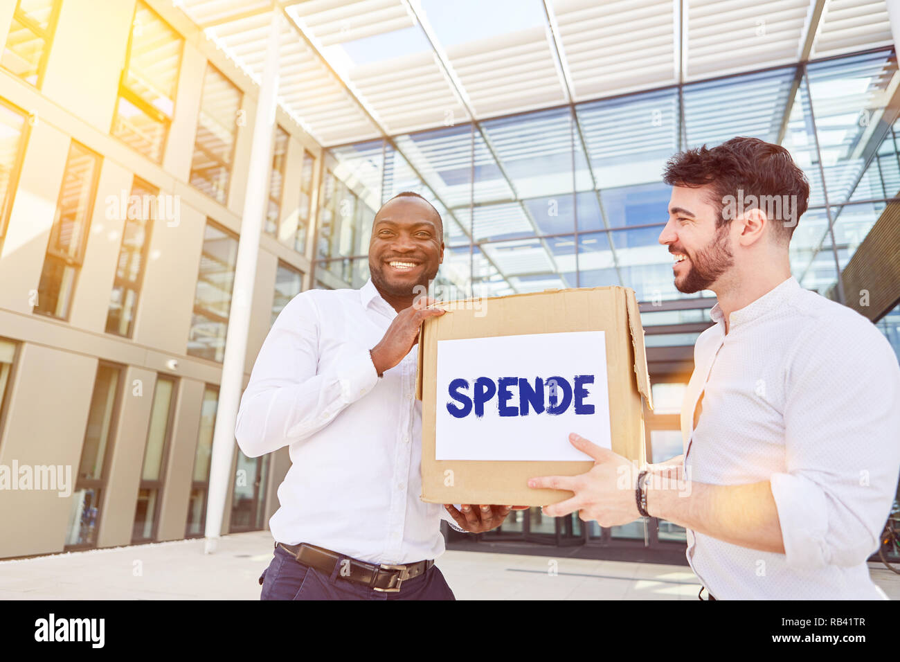 Business people of a company collects donations in donation action in front of the office with box saying in German 'Spende' (donation) Stock Photo