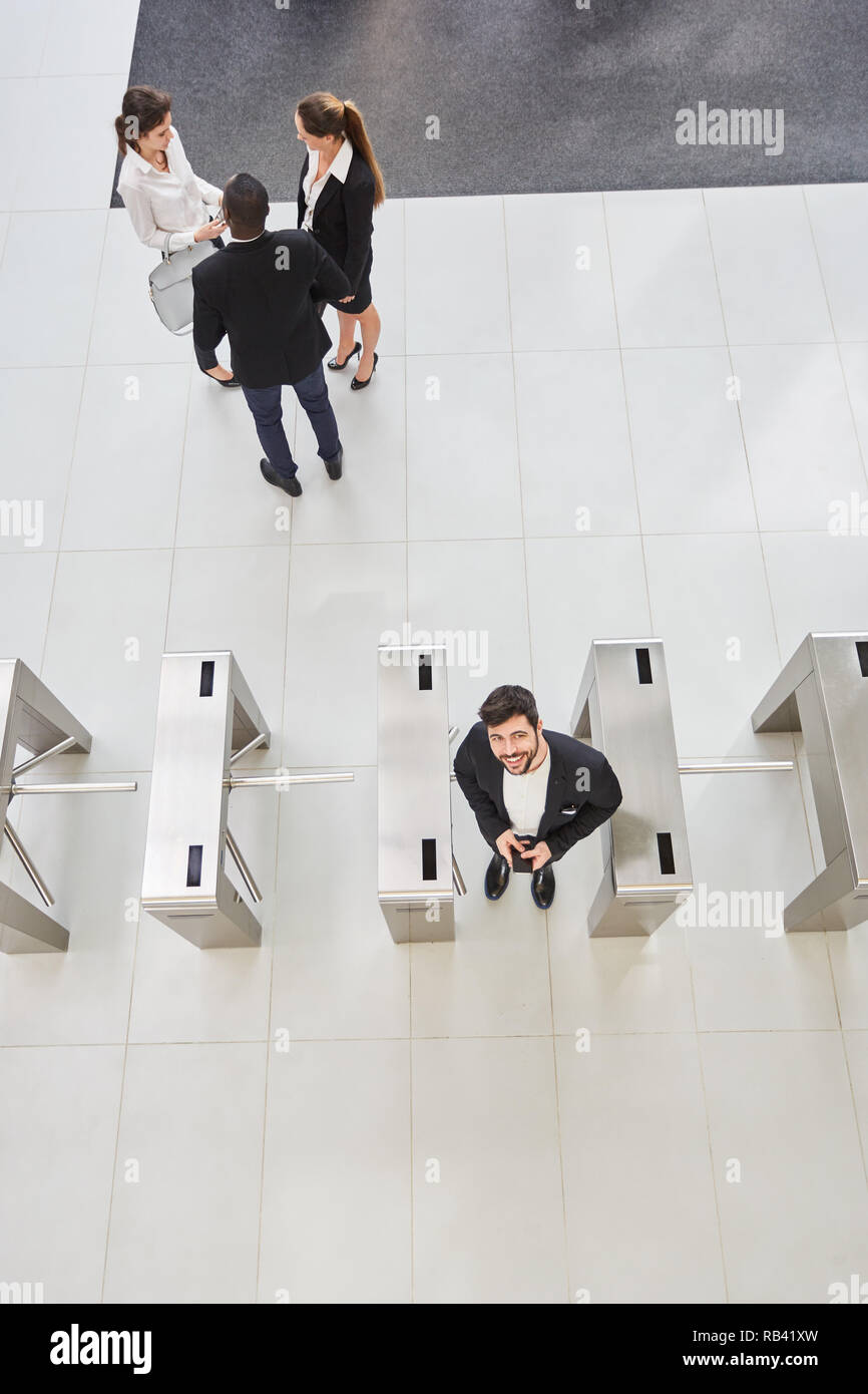 Businessman stands at the turnstile for access control in the foyer of a corporation Stock Photo