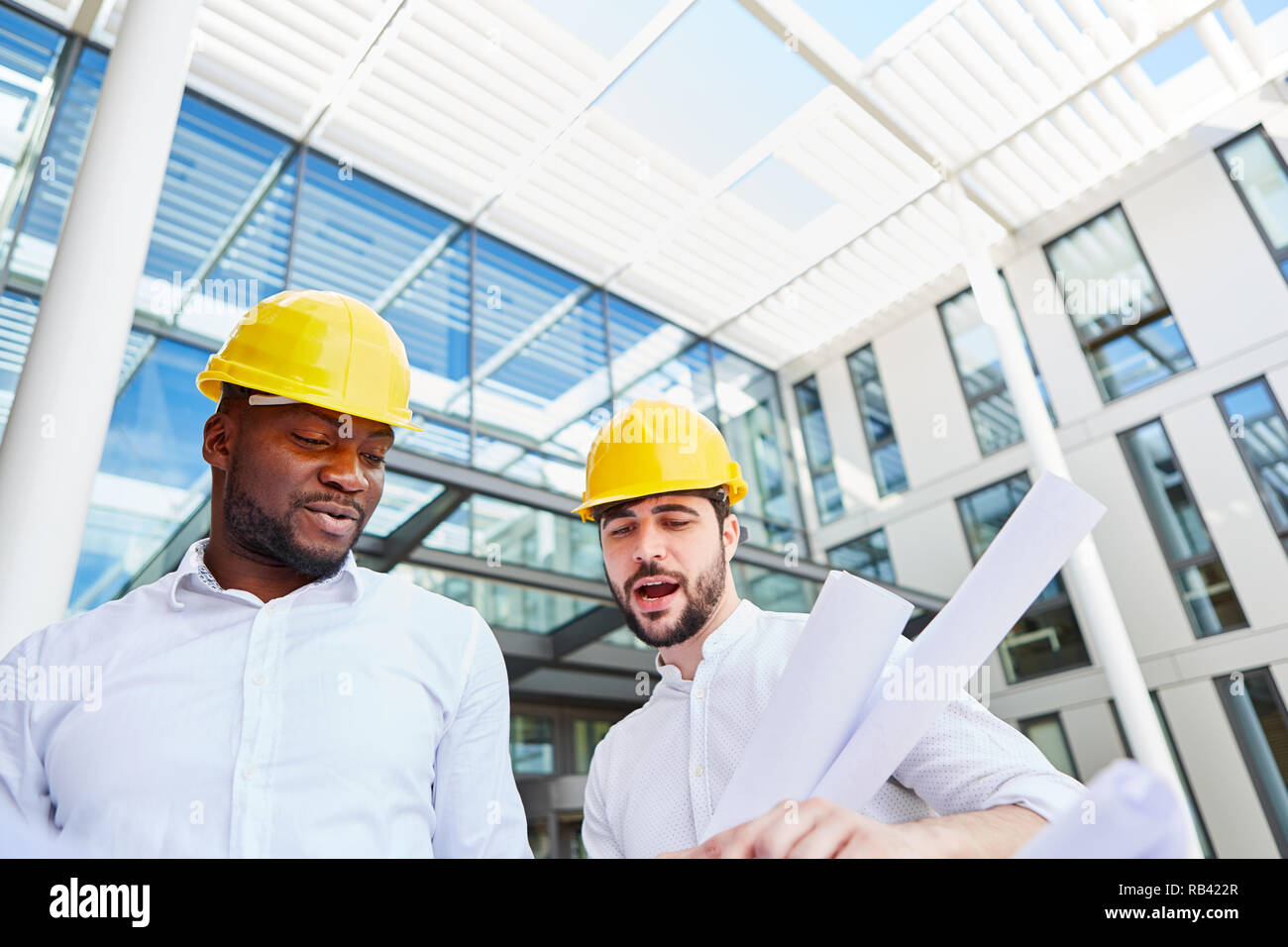 Two architects or construction manager with blueprint working in team in front of an office house Stock Photo