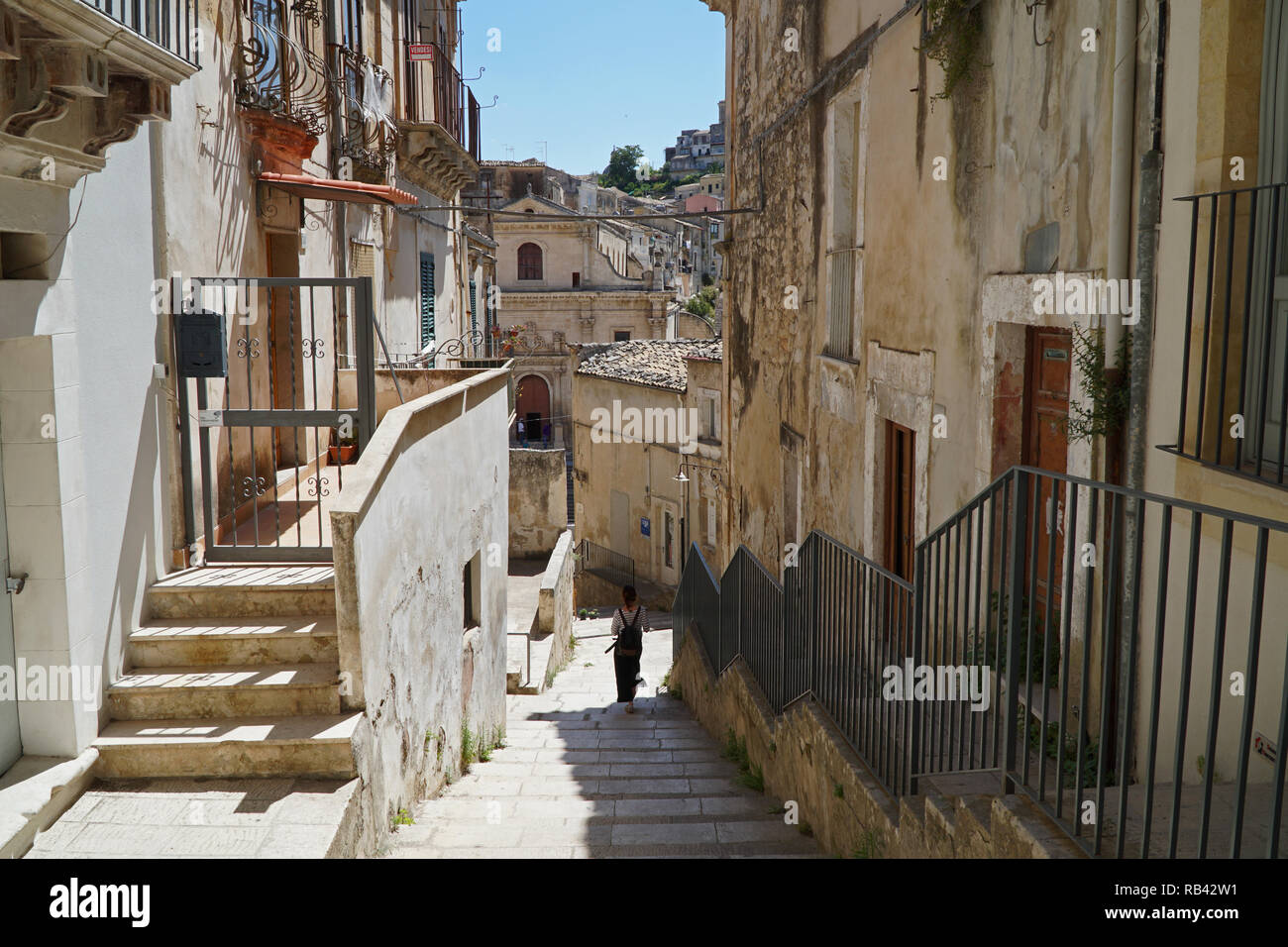 View of the narrow streets and steps of old Ragusa with a woman walking down a narrow street Stock Photo