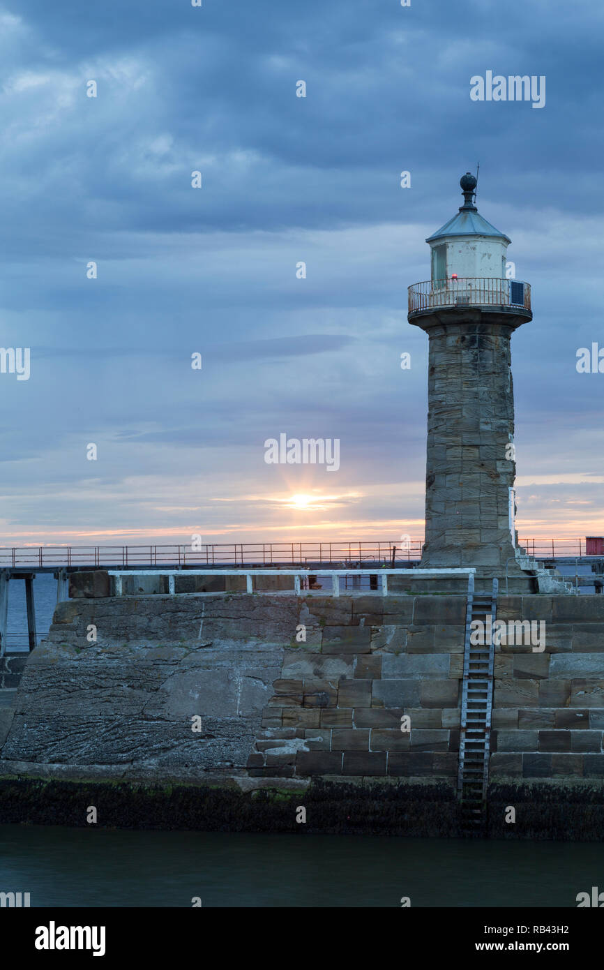 UK, Whitby lighthouse and dramatic sky at dawn. Stock Photo