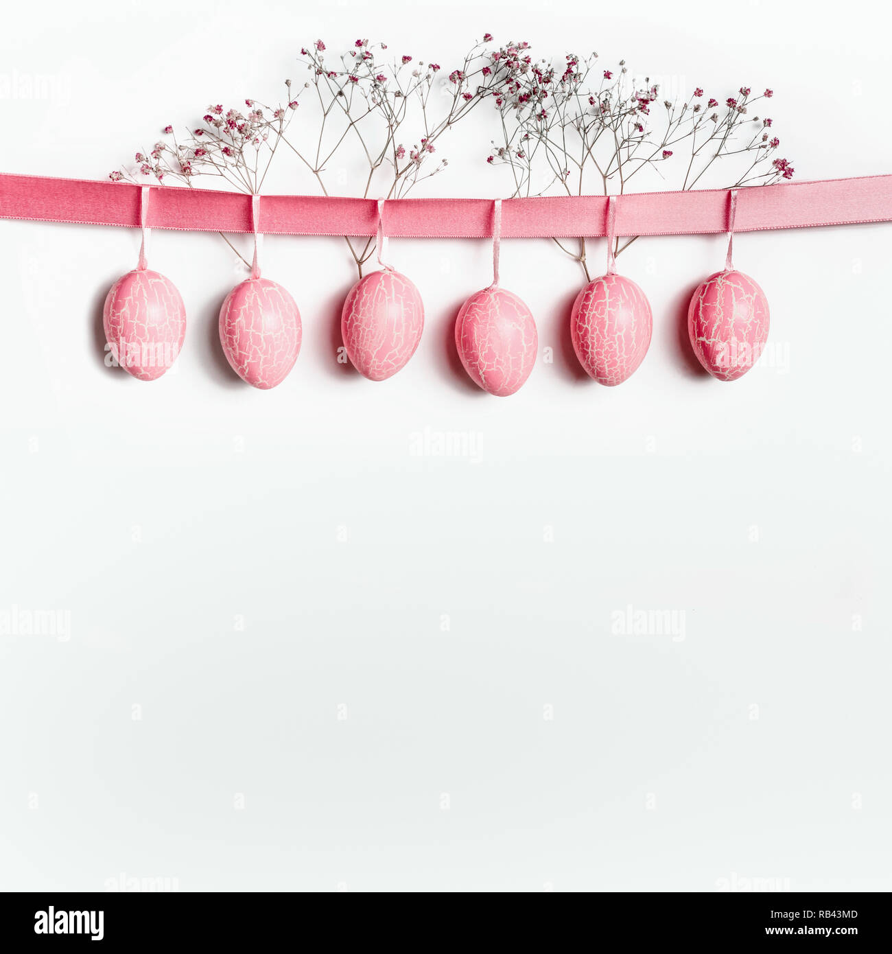 Easter background with hanging pastel pink Easter eggs on ribbon with ...