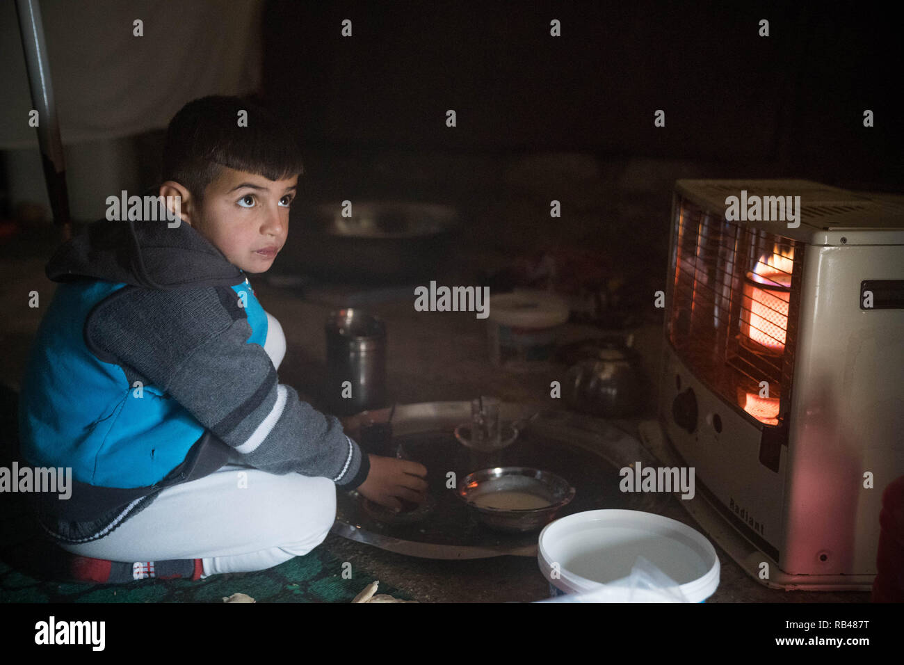 Zakho, Duhok Governorate, Iraq. 29th Dec, 2018. A Yazidi child sitting in front of a heater in a cold winter morning.The Bajed Kandala IDP camp is hosting over 9000 Yazidi Internally Displaced Persons from Sinjar where they lost their homes to the ISIS militants in August 2014. Credit: Geovien So/SOPA Images/ZUMA Wire/Alamy Live News Stock Photo
