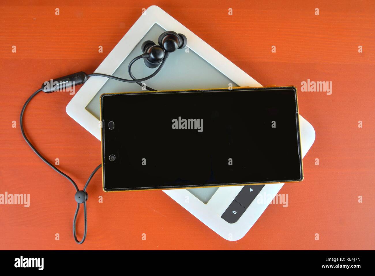 Mobile phone, ebookreader and wireless headset on claret background