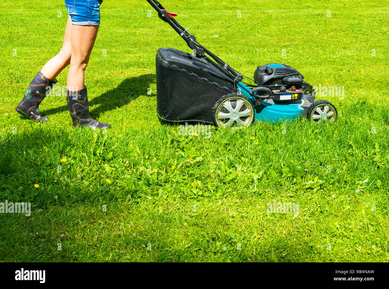 Beautiful girl cuts the lawn, Mowing lawns, Lawn mower on green grass