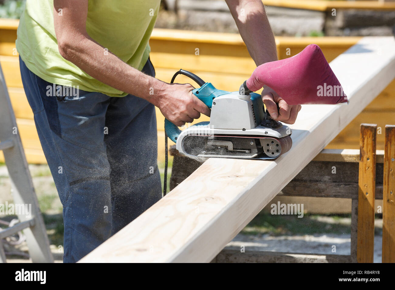 Carpenter softening edges on construction beams with electric belt