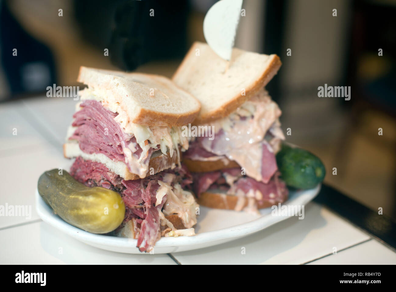 Kosher deli combination sandwich pastrami corned beef tongue cole slaw and Russian dressing on seeded Jewish rye bread with garlic and sour pickles Ne Stock Photo