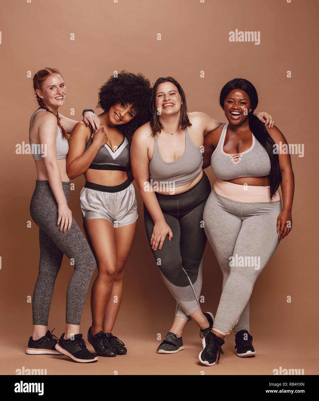 Group of women of different race, figure type and size in sportswear  standing together over brown background. Diverse women in sports clothing  looking Stock Photo - Alamy