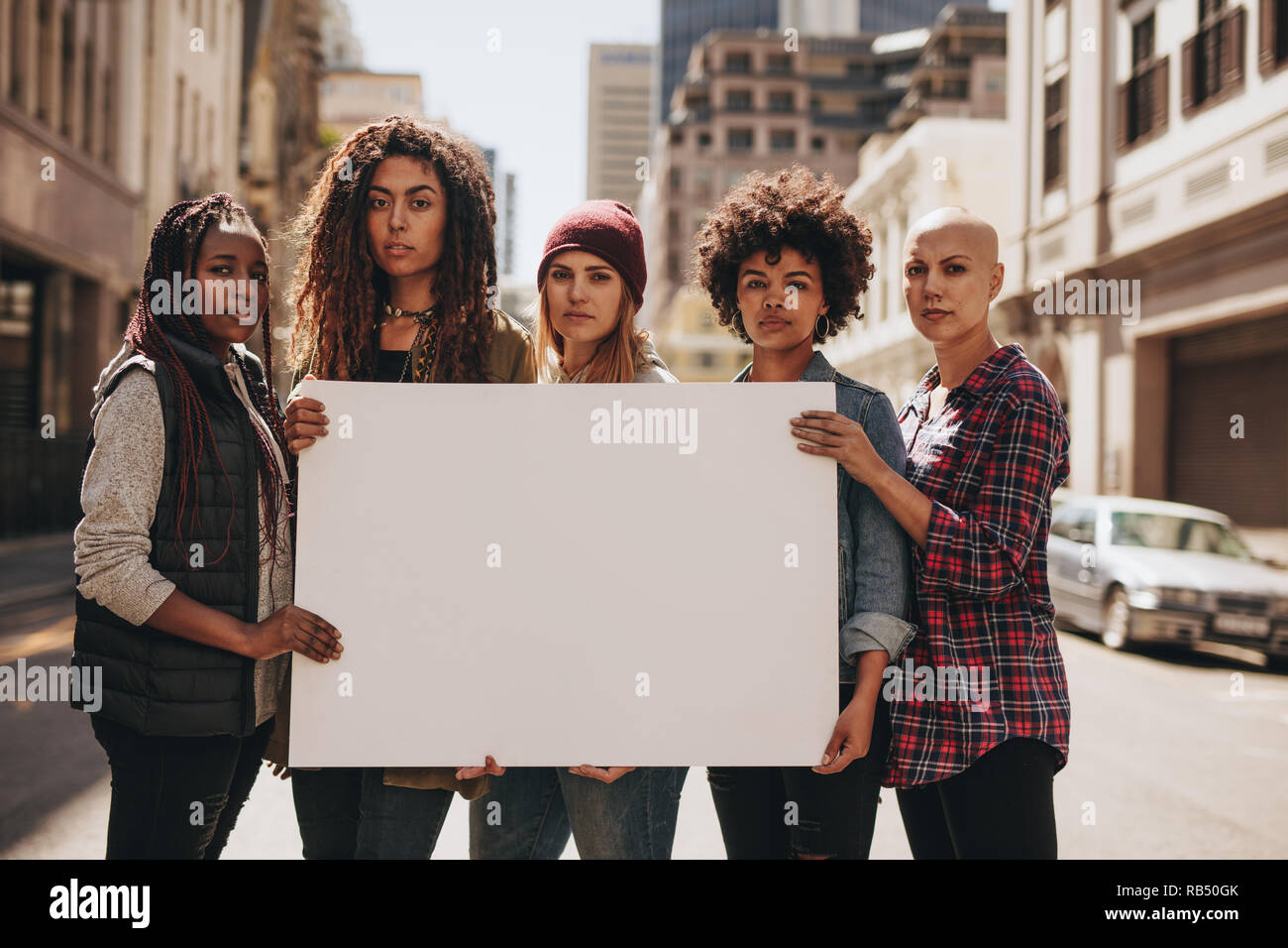 Group of females protesters on road with a blank signboard. Females holding blank banner during a protest. Stock Photo