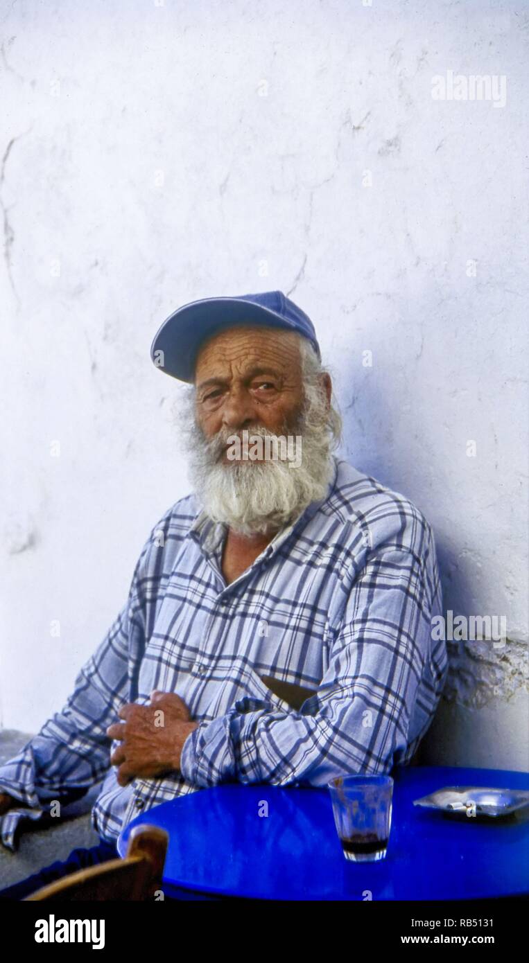 Elderly MAn sat relaxing outside a Kafeneio, Coffee Shop, Tholaria Village, Greek