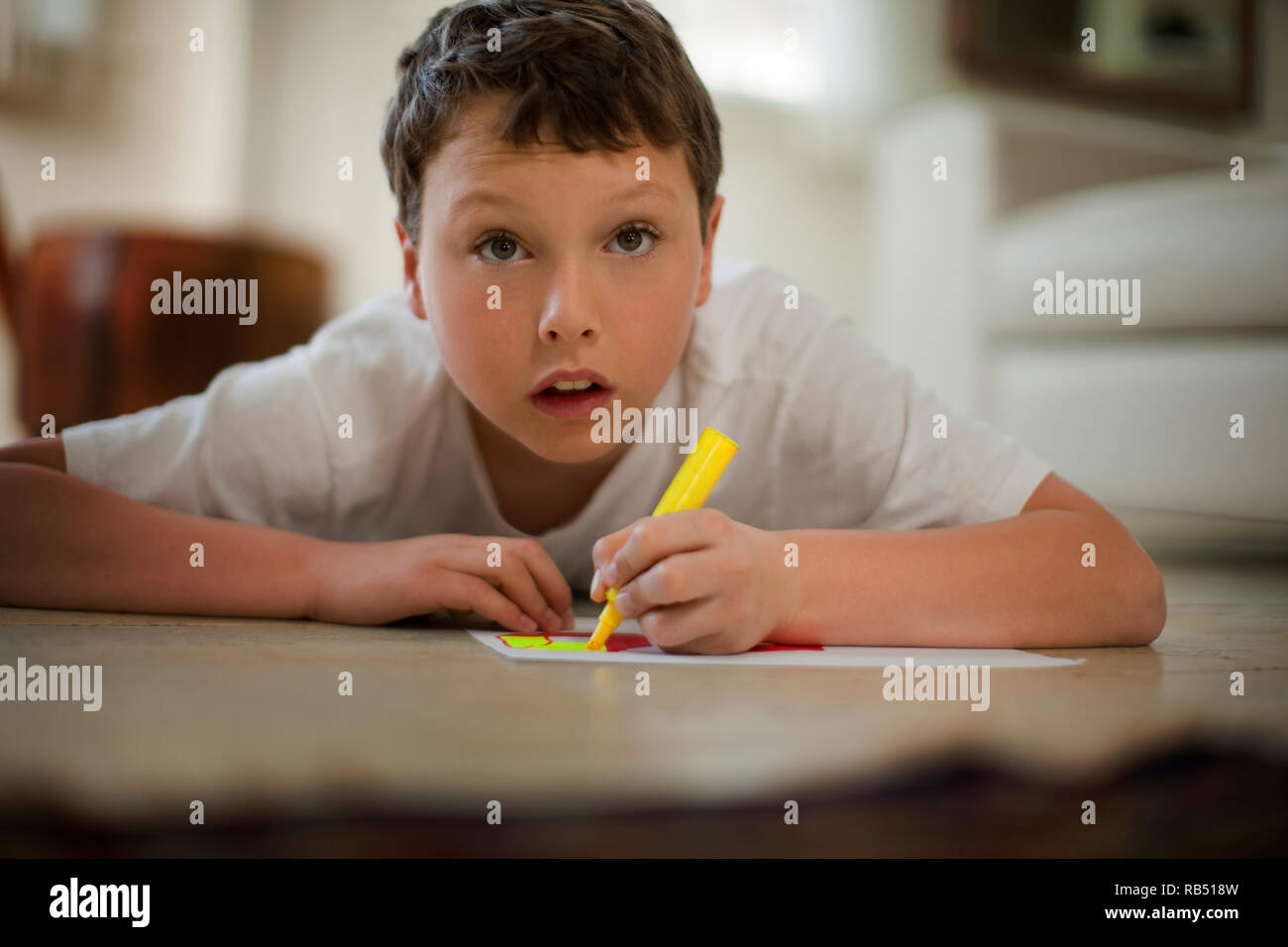 Boy lying down coloring in pictures. Stock Photo