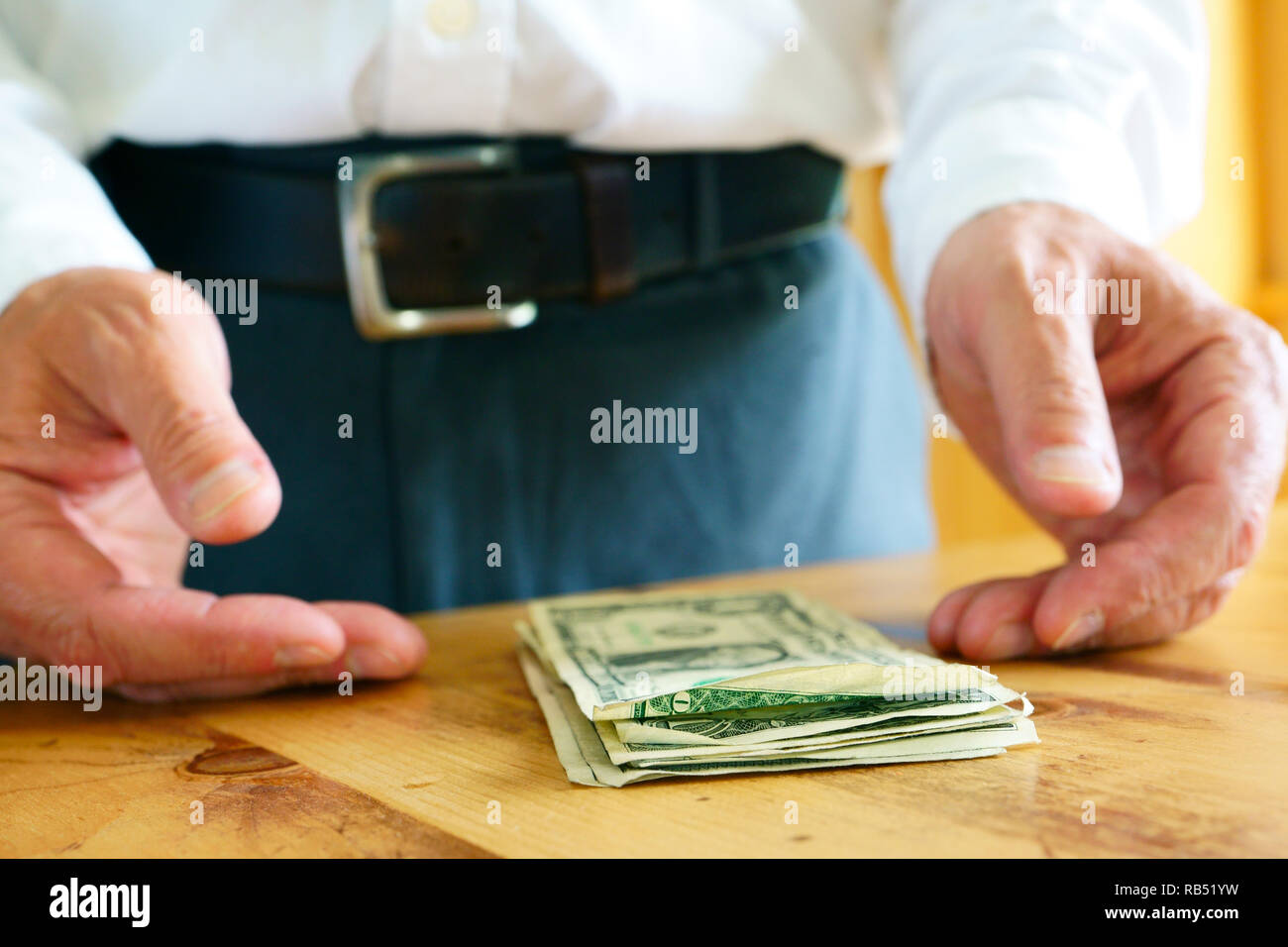 A caucasian man is counting his money on the wooden table. Stock Photo