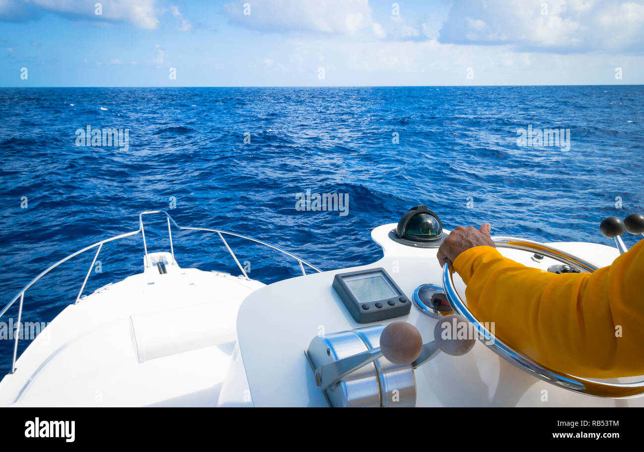 Hand of captain on steering wheel of motor boat in the blue ocean due