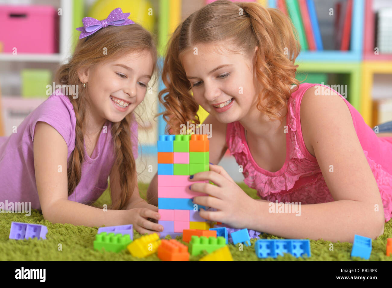 Cute girls playing with colorful plastic blocks Stock Photo