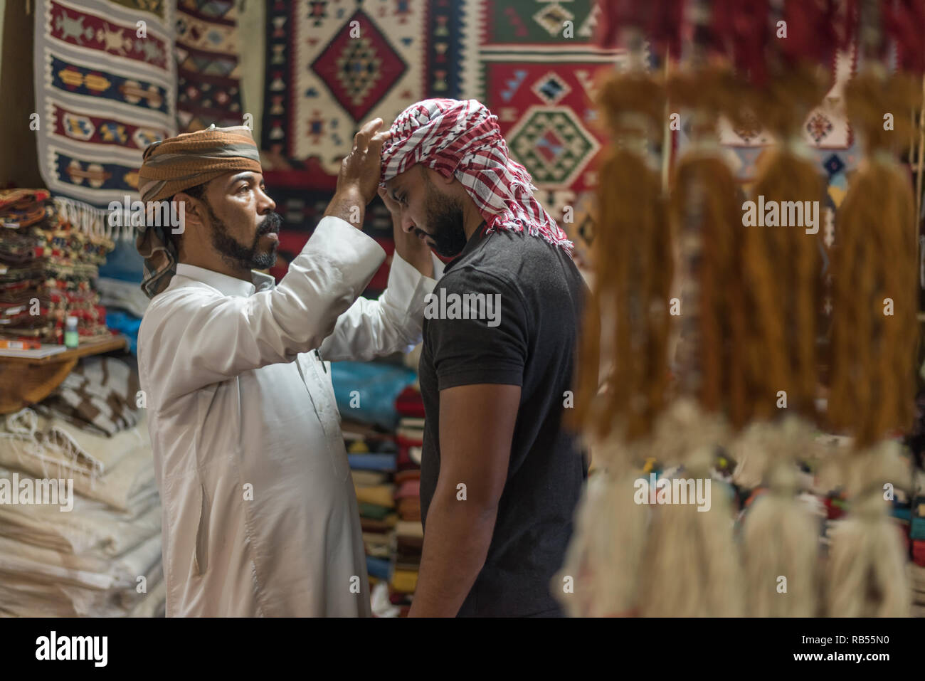 Portrait of a bedouin Arabic man helping another with wearing a head scarf bedouin style in Siwa Egypt Stock Photo
