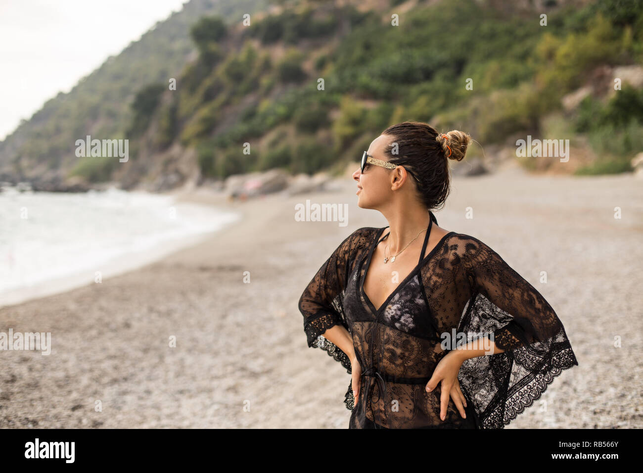 Young female wearing black lace tunic enjoying beatiful bay. Stock Photo