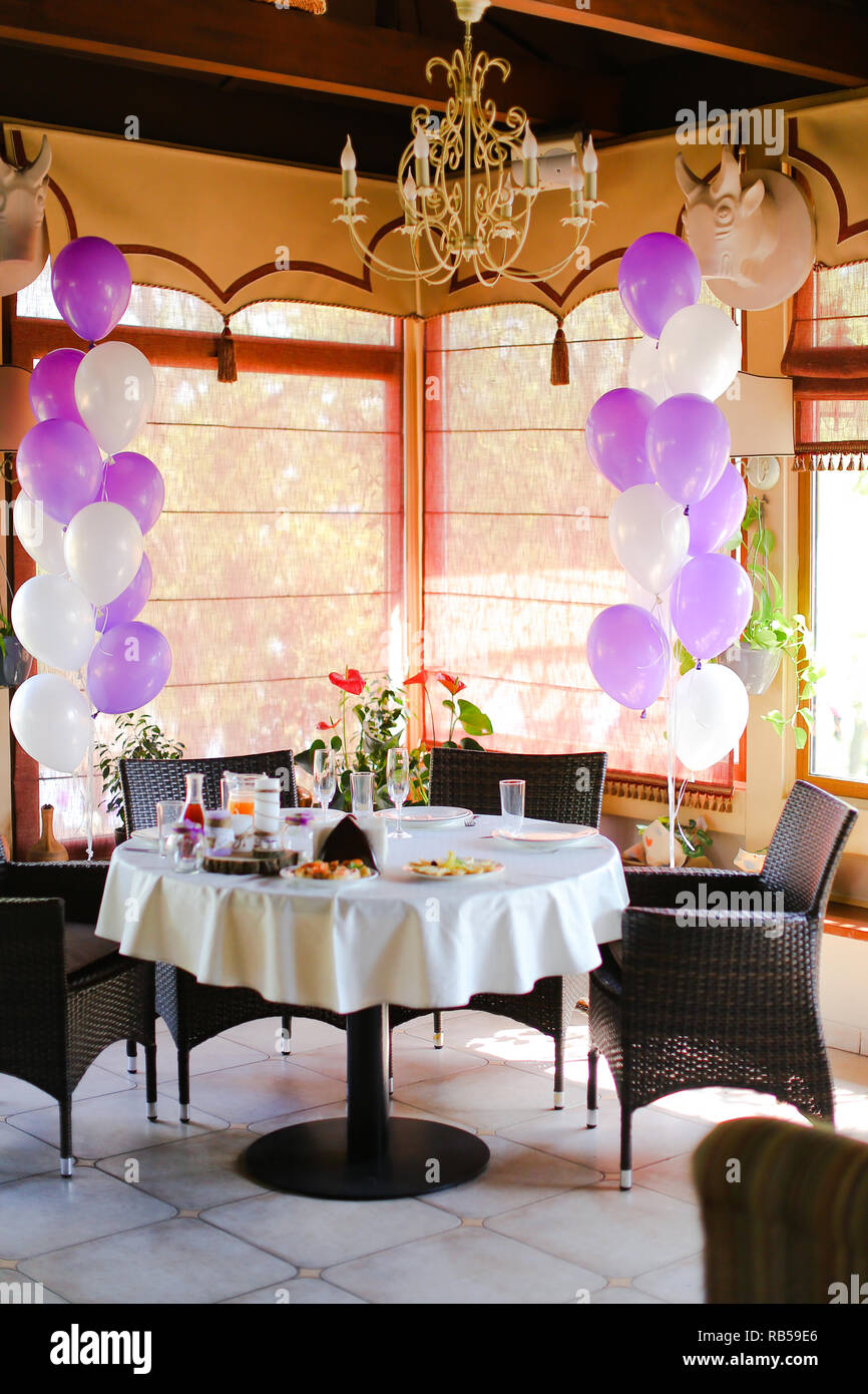 Food on table at cafe and white violet ballons. Stock Photo