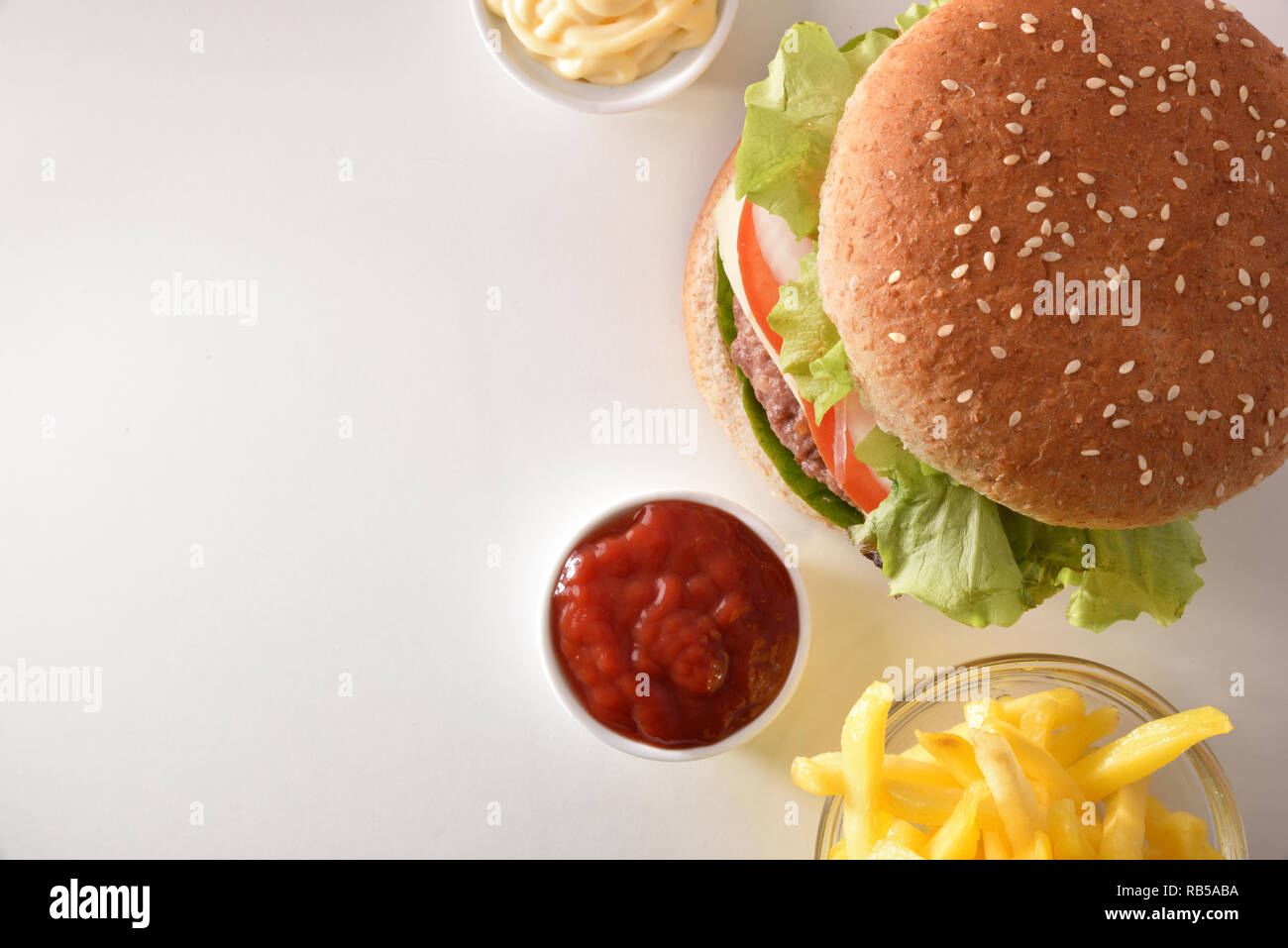 Burger with chips and sauces on white table. Top view. Horizontal composition. Stock Photo