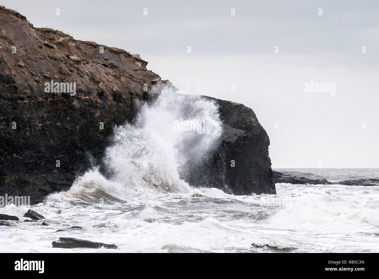 Waves crash on rocks at Whitby, England, during a period of rough seas ...