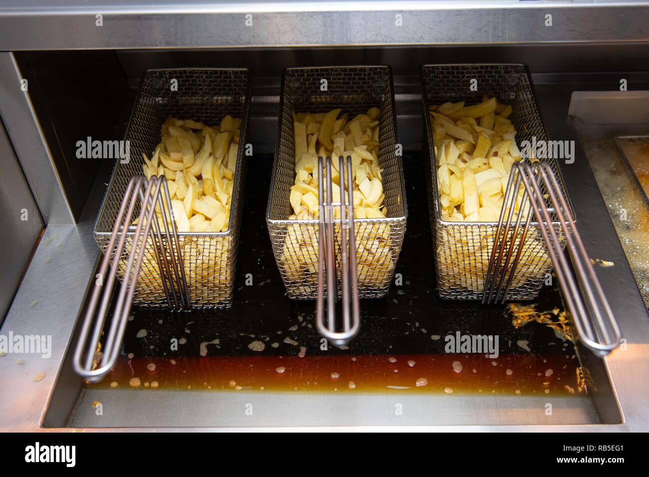Potato chips ready to cook in a deep fat fryer in a chip shop in the UK