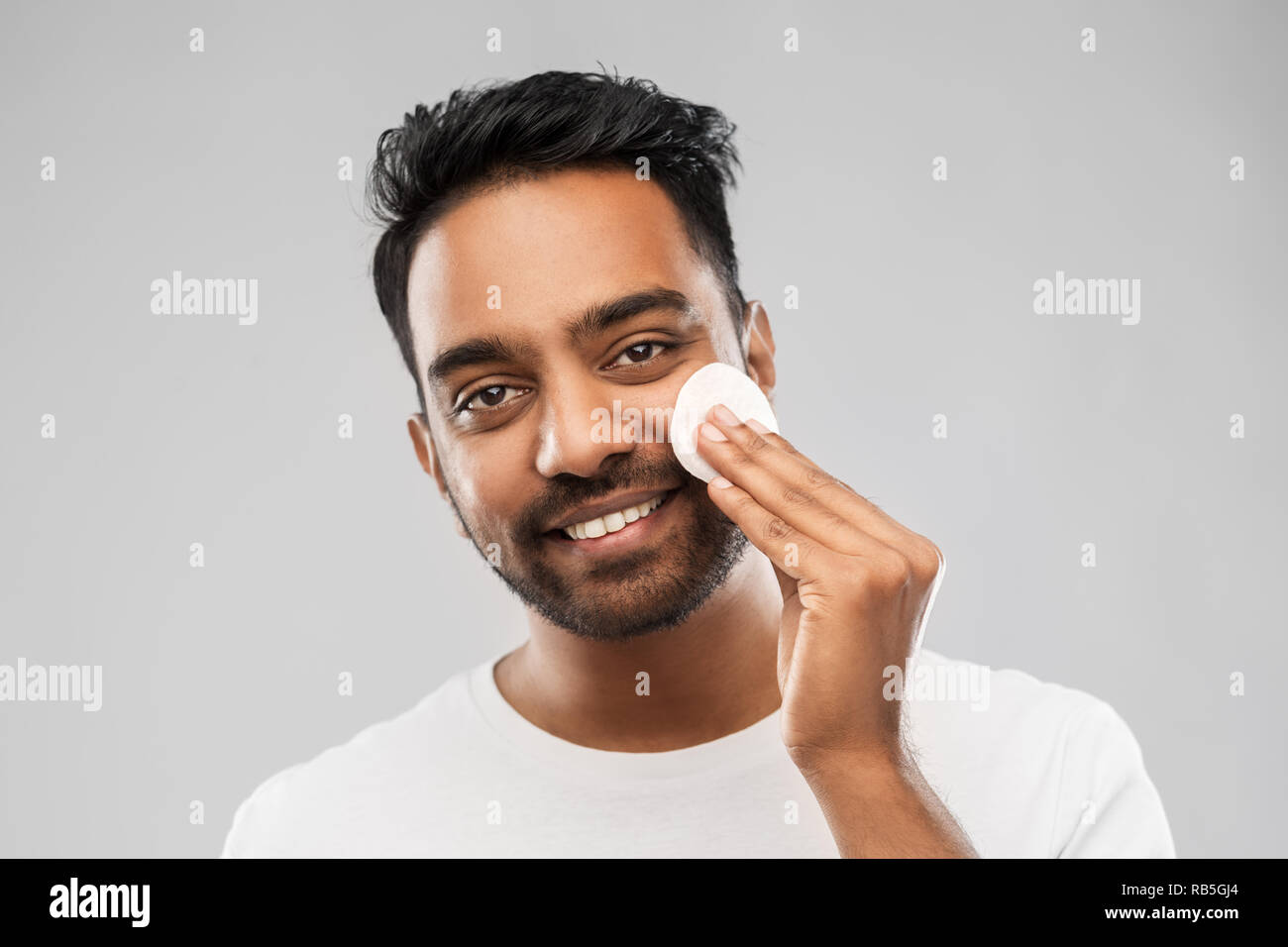 smiling indian man cleaning face with cotton pad Stock Photo Alamy