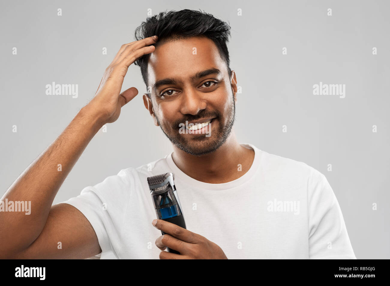 smiling indian man with trimmer touching his hair Stock Photo - Alamy