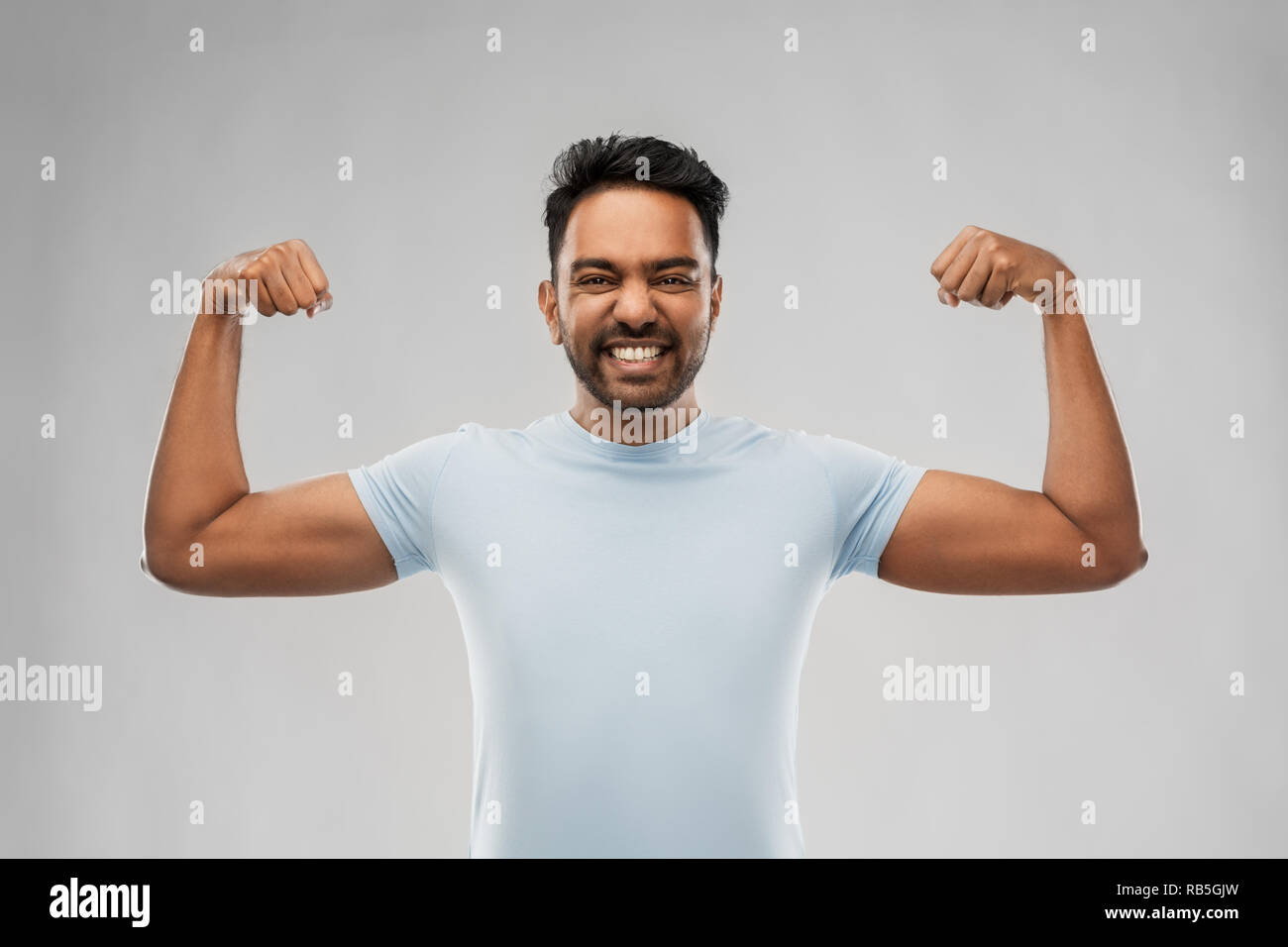 indian man showing biceps over grey background Stock Photo
