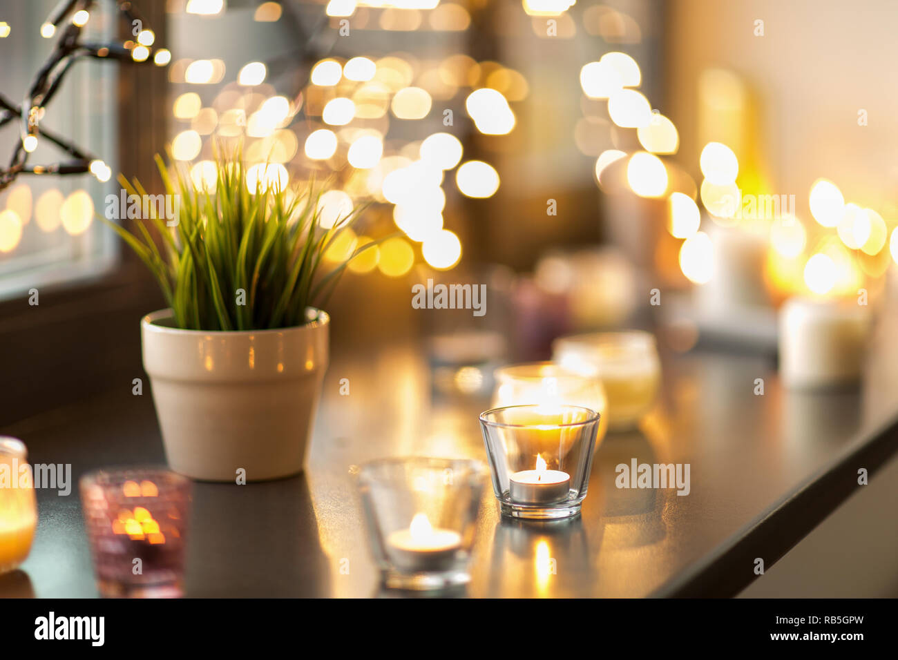 candles burning on window sill with garland lights Stock Photo - Alamy