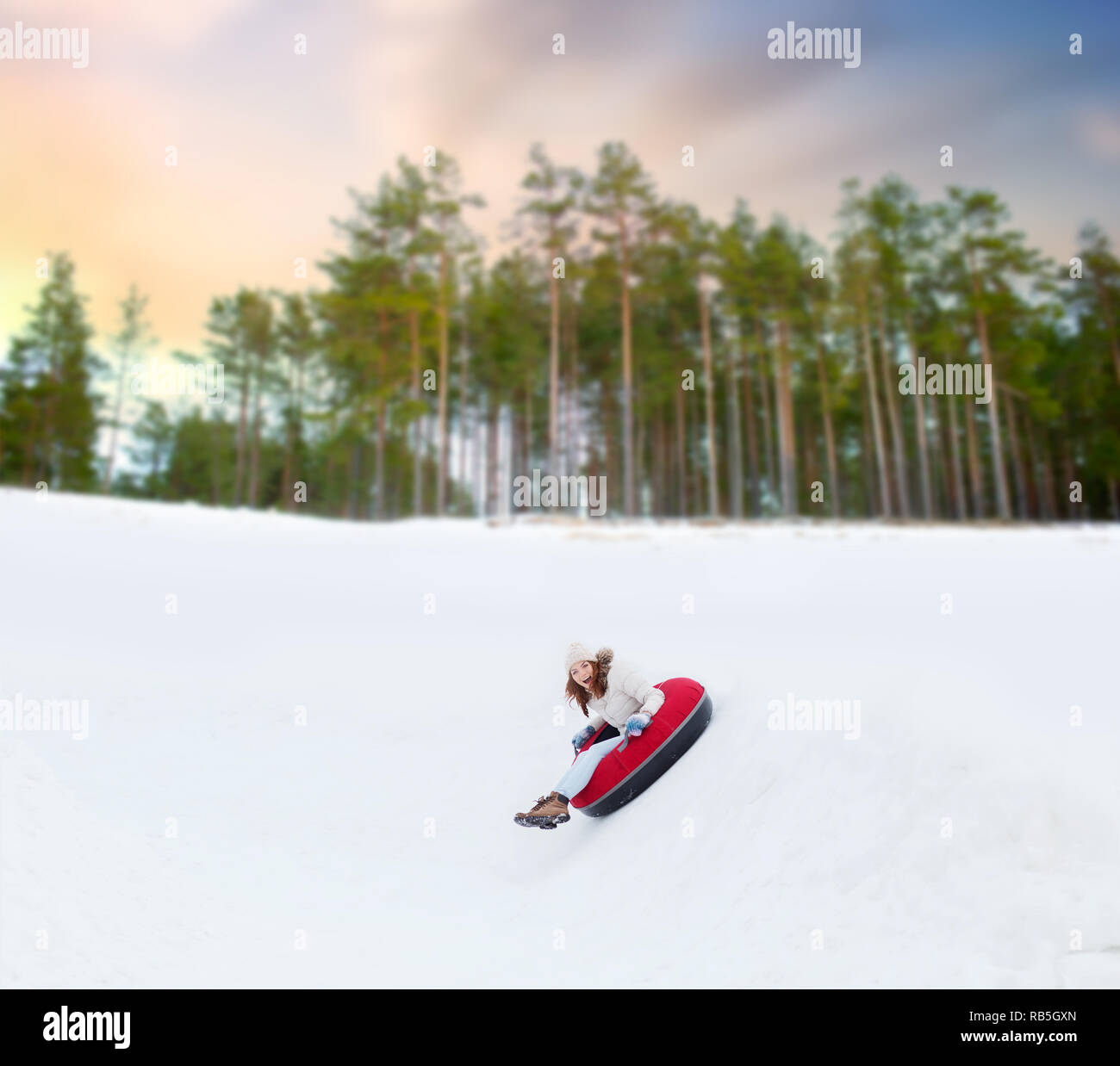 Woman sliding down a snow-covered slope in a Canadian forest