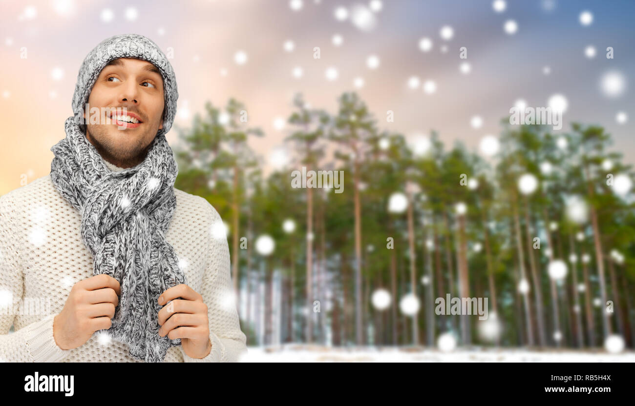 smiling man in hat and scarf over winter forest Stock Photo