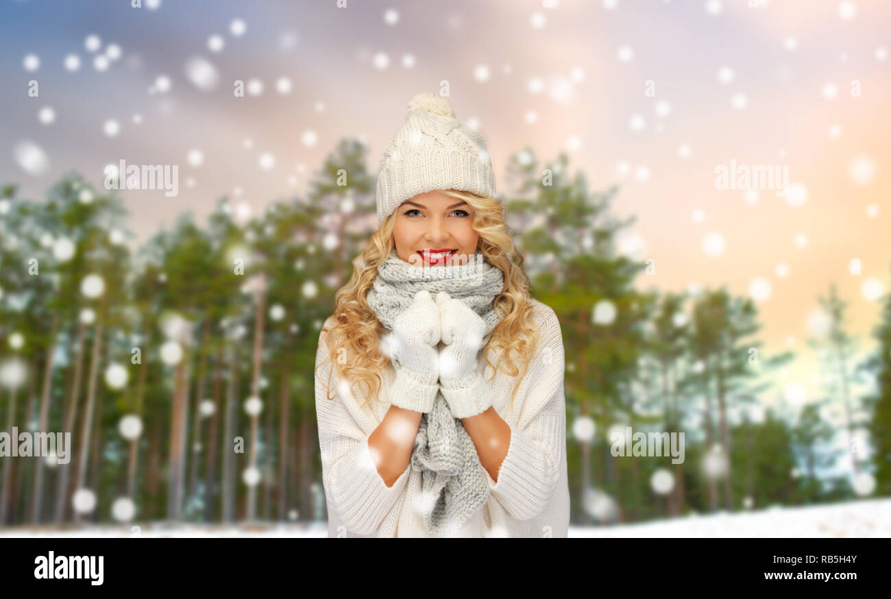 happy woman in hat and scarf over winter forest Stock Photo