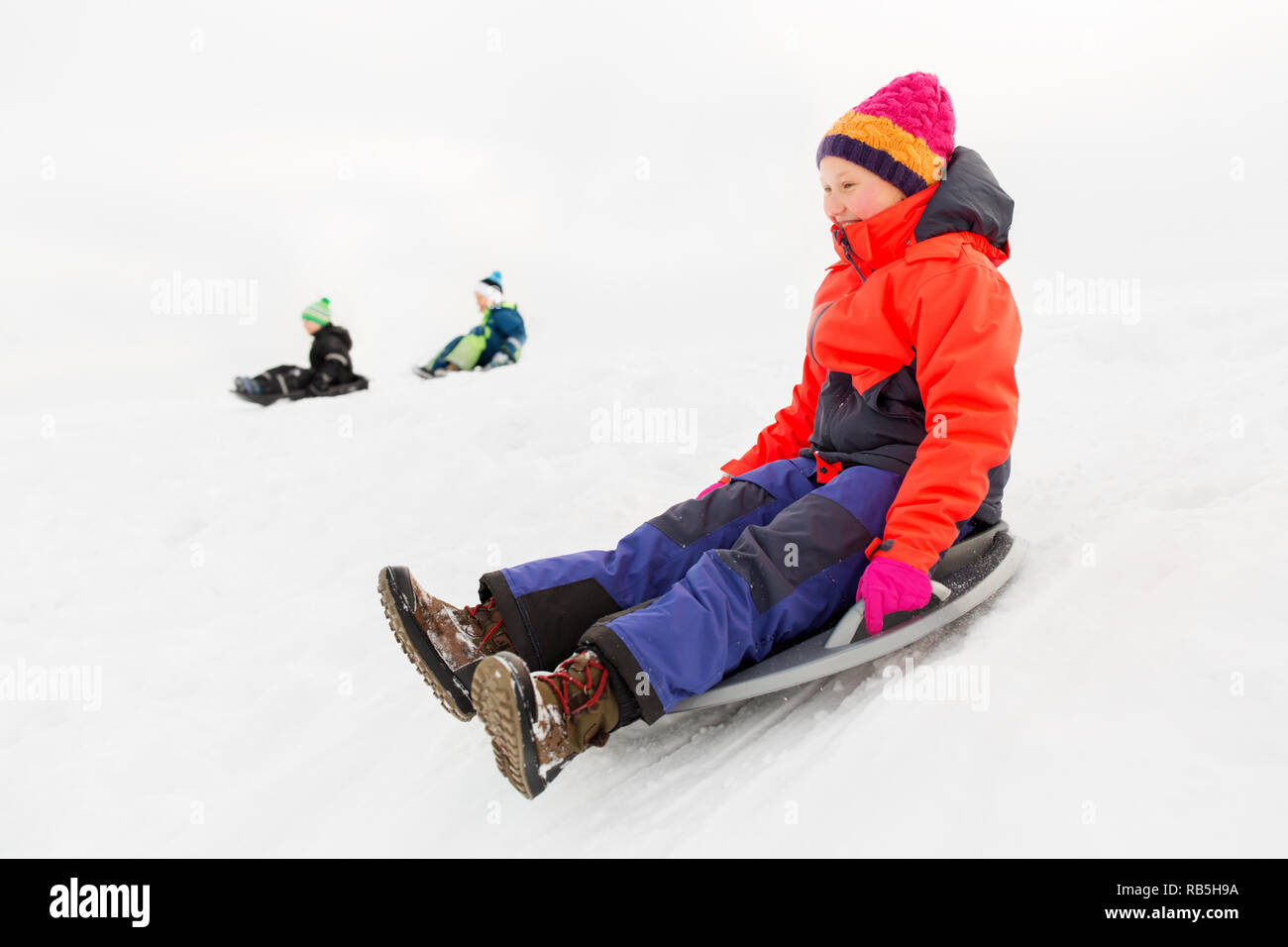 happy kids sliding on sled down hill in winter Stock Photo Alamy