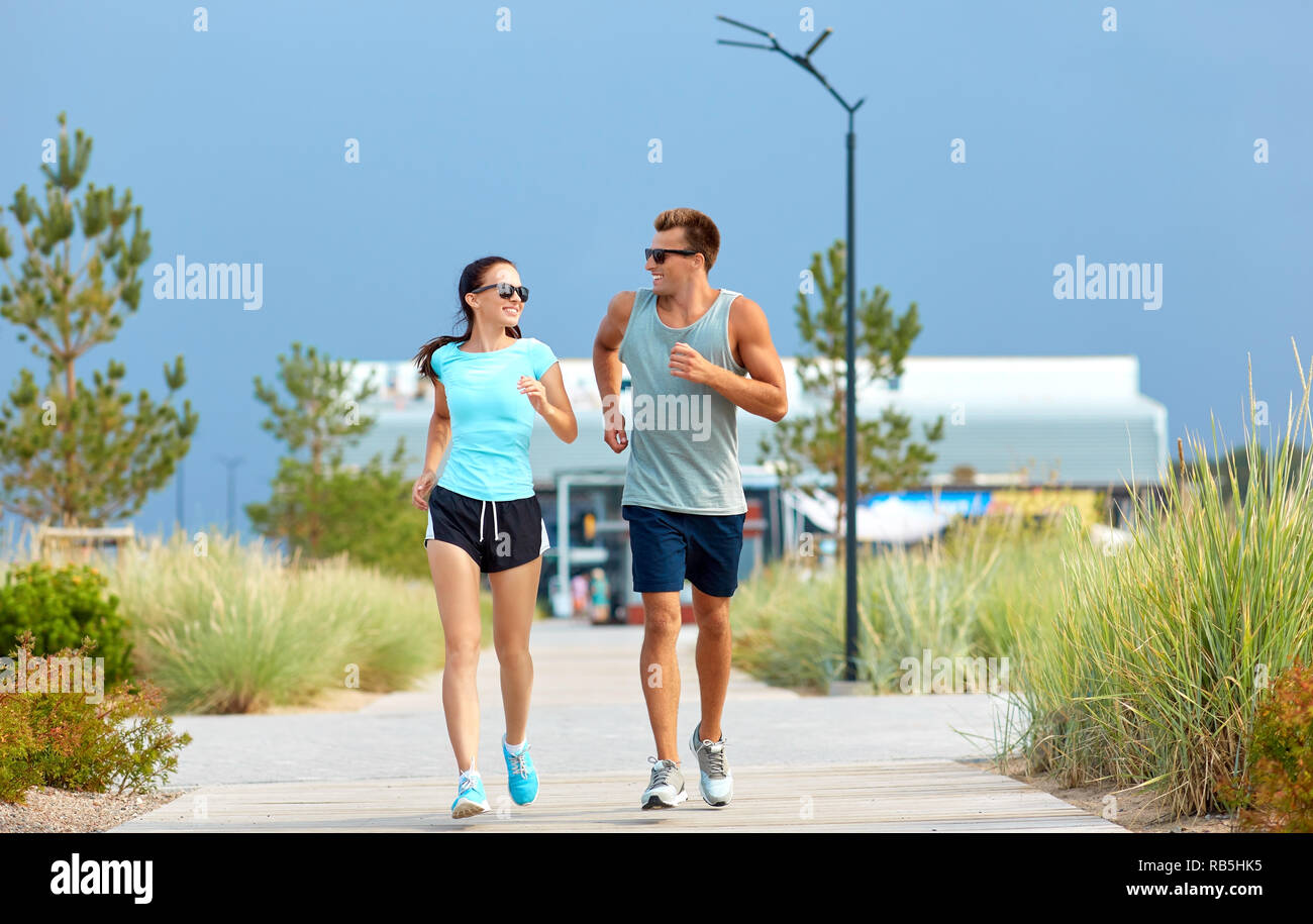 couple in sports clothes running along on beach Stock Photo - Alamy
