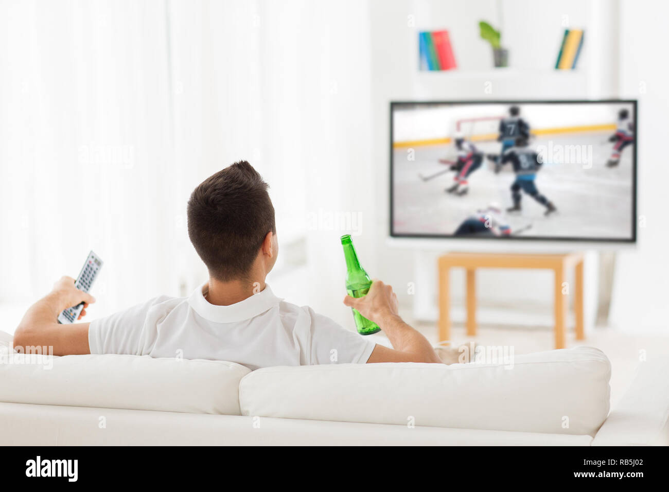 man watching ice hockey on tv and drinking beer Stock Photo