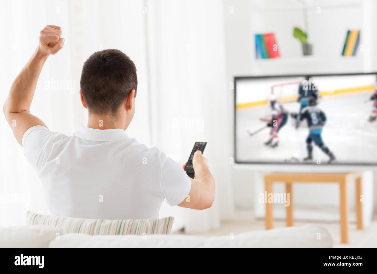 man watching ice hockey game on tv at home Stock Photo