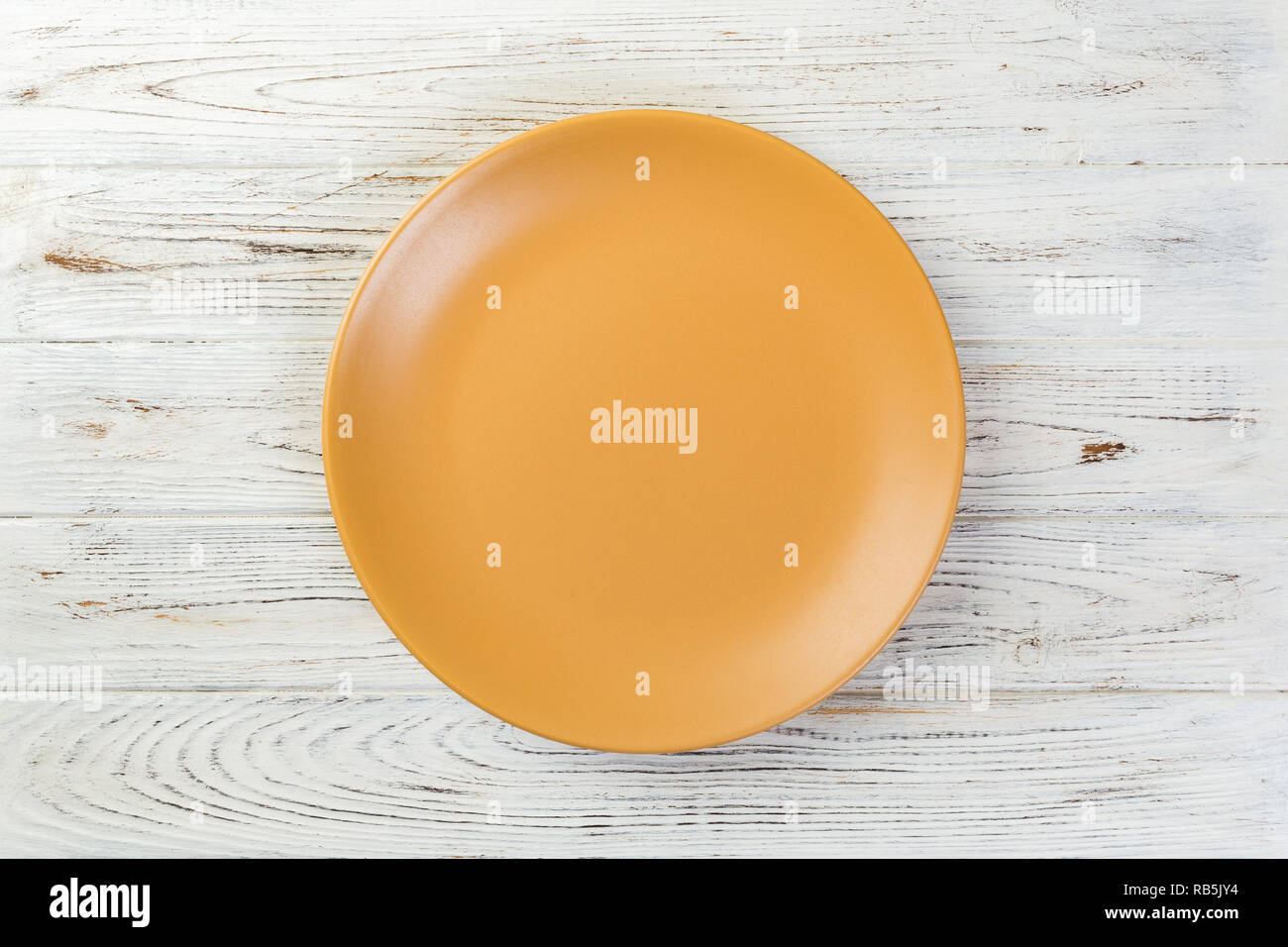 Directy above Empty yellow matte plate on white wooden background Stock ...