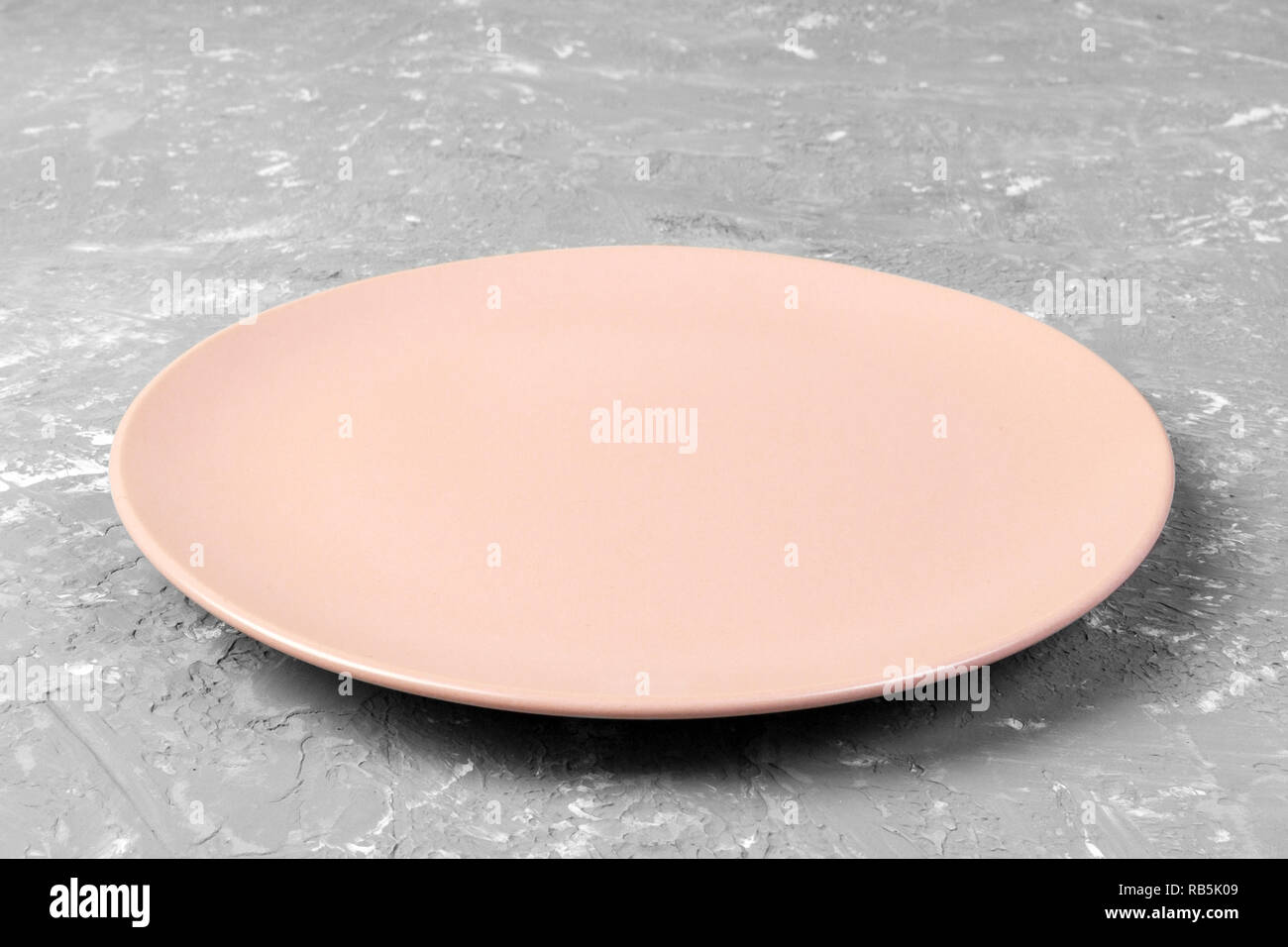 Top view of matte round empty rose plate on grey cement background copy ...
