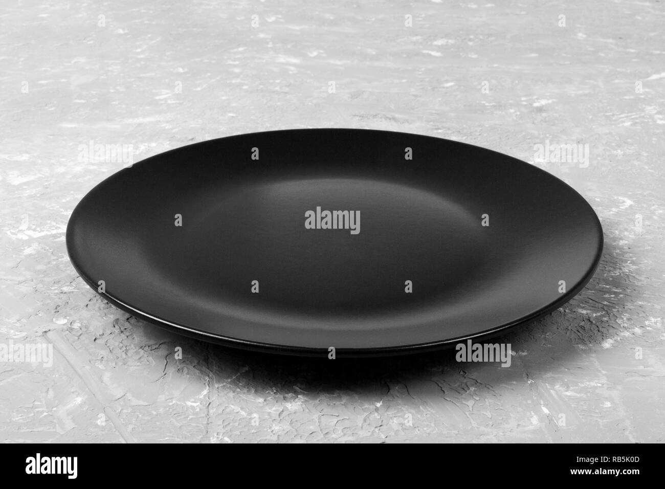 Top view of matte round empty black plate on grey cement background ...