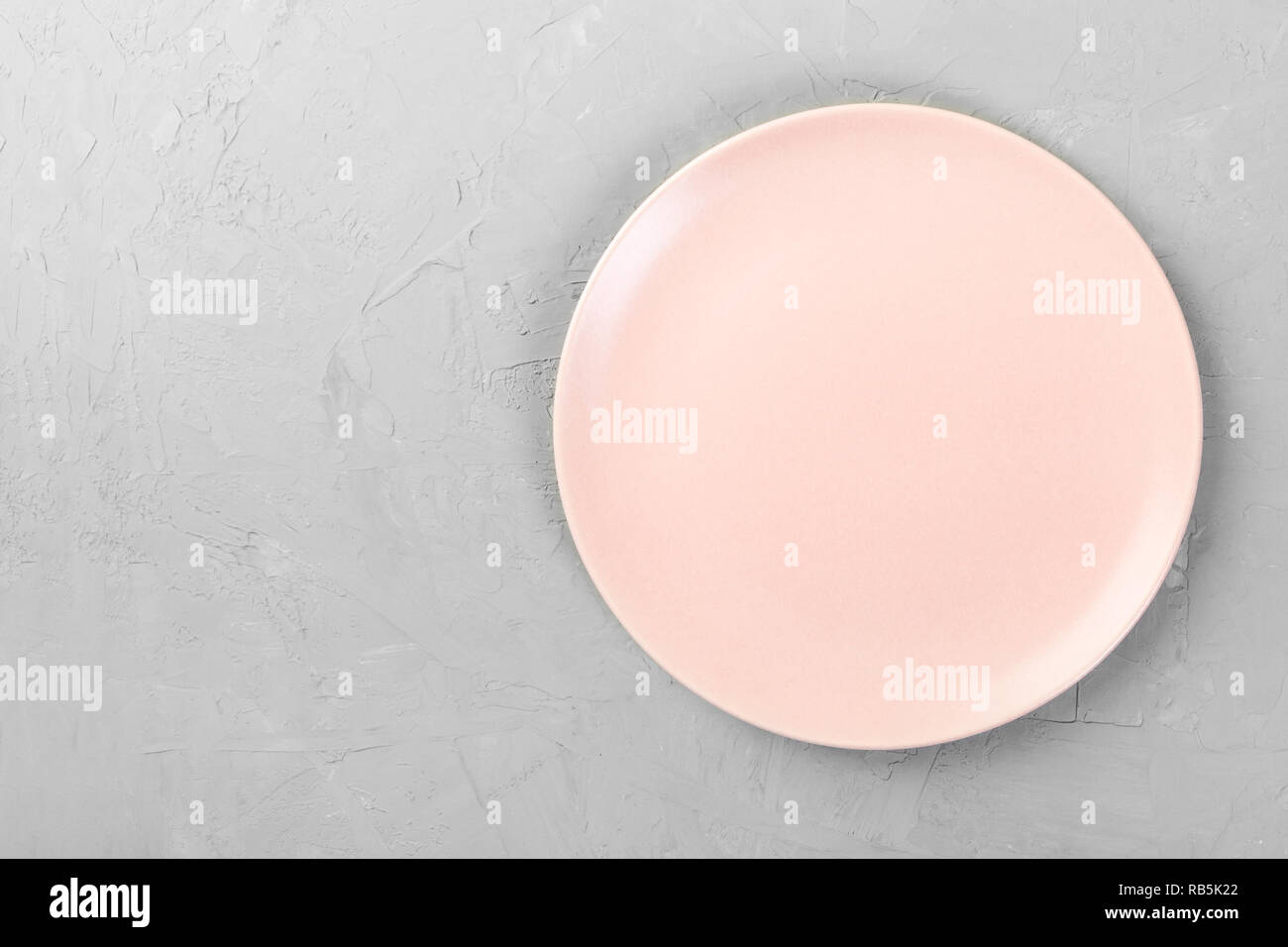 Top view of matte round empty rose plate on grey cement background ...
