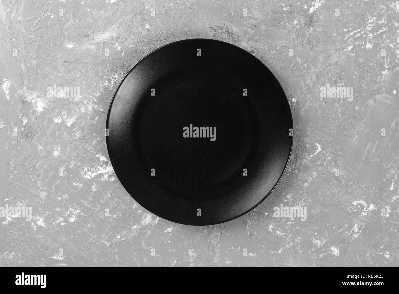 Top view of matte round empty black plate on dark cement background ...